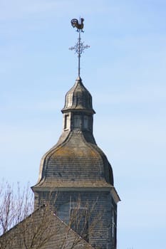 old church tower covered with moss and a weather vane