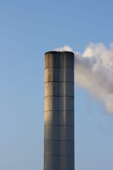 Large chimney sent clouds of steam into the blue sky