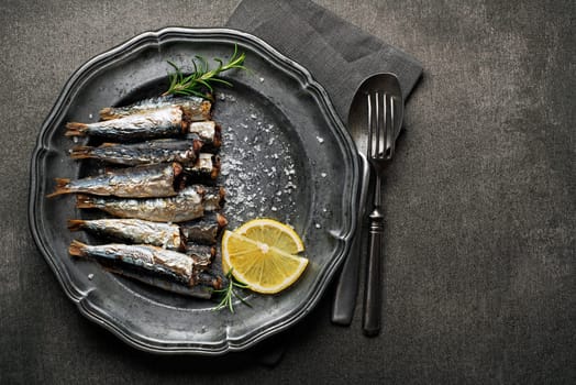 Fried sardines with salt and herbs on rustic background