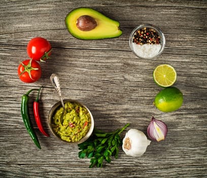 Avocado guacamole with fresh ingredients on wooden table