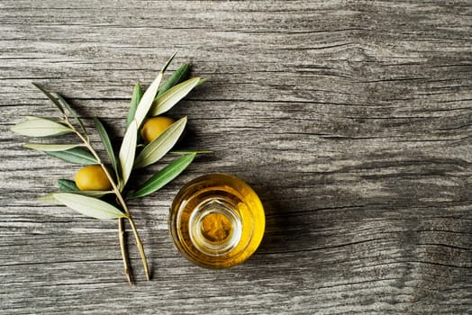 Olive oil and olive branch on wooden table