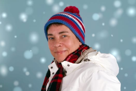 Laughing middle-aged woman in winter clothes on a blue background