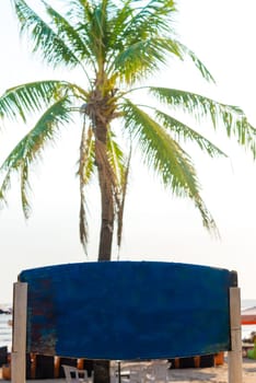 Blank blue vintage signboard with copy space and palm tree in background. Vacation and travel concept