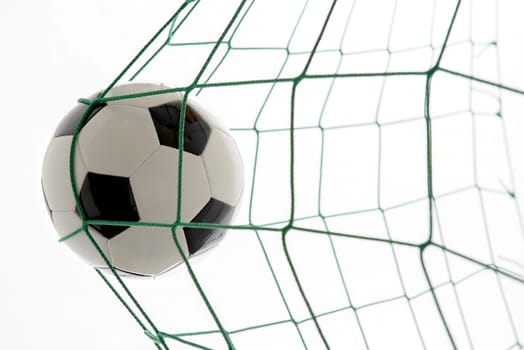 soccer ball in green goal in front of white background