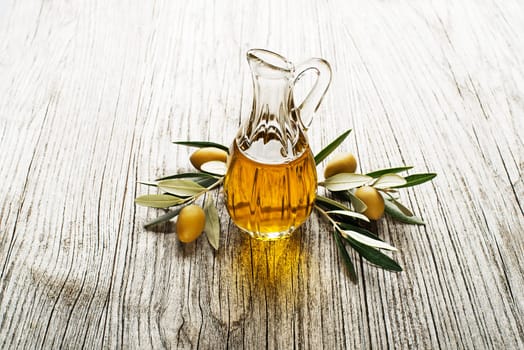 Olive oil and olive branch on a wooden background