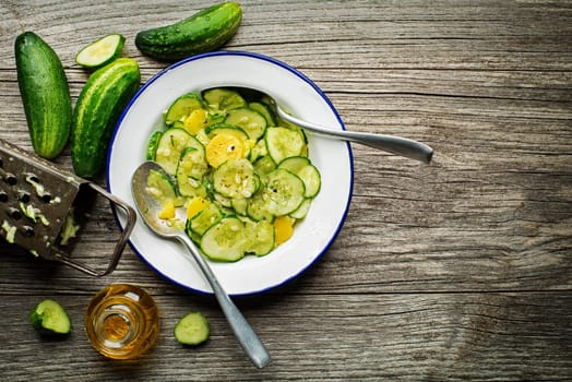 Fresh cucumber salad with potatoes on wooden background