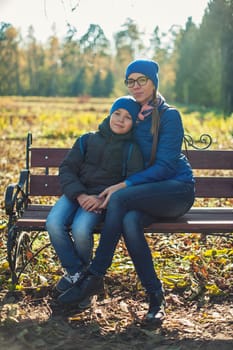 Mother and son at autumn park in sunny beauty day