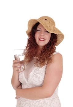 A young pretty woman in a beige dress and straw hat standing waist.up and smiling, with a glass of water, isolated for white background.