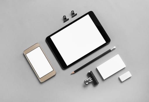 Gadgets with blank screens and stationery on gray paper background. Template for placing your design. Top view.
