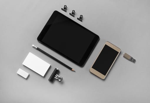 Blank stationery and gadgets at gray paper background. Top view.