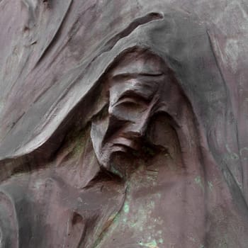 Detail of a mourning sculpture on a cemetery. (Religion, faith, suffering concept).