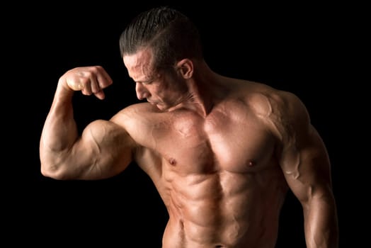 Power athletic man with great physique. Strong bodybuilder showing his biceps.