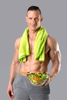 Powerful athletic man with great physique eating a healthy salad.
