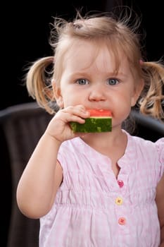 Cute little girl in pink dress eating watermelon fruit