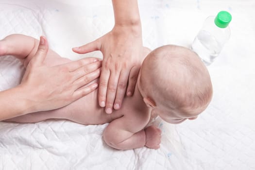 Three month baby boy receiving back massage from a female massage therapist