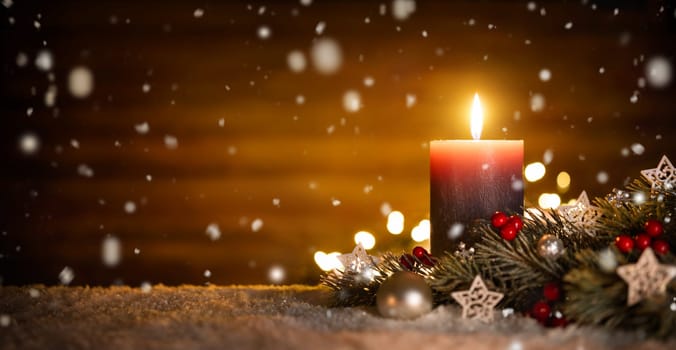 Burning candle,Christmas decoration and wooden background in falling snow,elegant low-key shot with festive mood