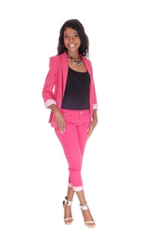 A gorgeous African woman standing in a pink suit with long curly.black hair and silver high heels, isolated for white background.