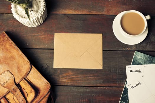 Opened craft paper envelope , autumn leaves and coffee on rustic wooden table