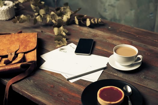 Opened craft paper envelope , autumn leaves and coffee on rustic wooden table