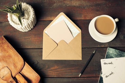 Opened craft paper envelope , autumn leaves and coffee on rustic wooden table