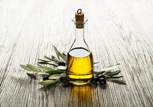 Olive oil and olive branch on a wooden background