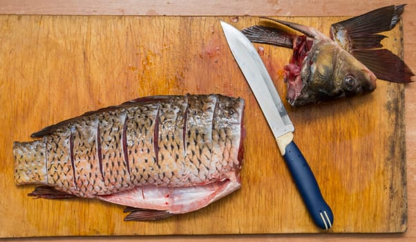 The brushed and cut fish lies on the cutting board, next to it lies a knife