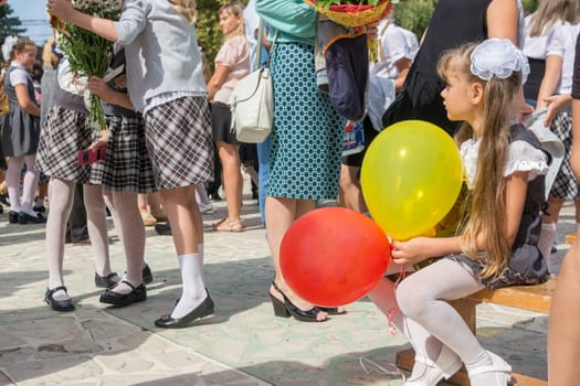 Anana, Russia - September 1, 2017: The first-grader looks sadly at a meeting of girlfriends on the feast of the first of September