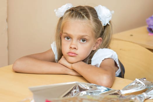A sad girl at her desk at the lesson of the first of September