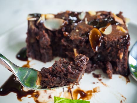 Close up sliced brownies on white plate with fork