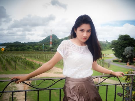 A portrait of a beautiful asian woman in the white shirt standing on the balcony