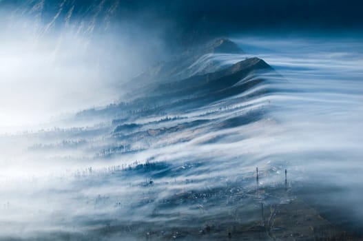 Mist Flowing over Cemoro Lawang and into Crater Gunung Bromo or Mount Bromo area Java Indonesia.