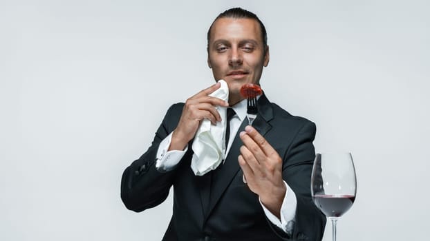 Portrait of a young man in image of maniak with knife, fork and and a piece of raw meat on a plate. Man in suit. The image in the style of Halloween