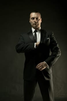 The attractive mature man in black suit on dark studio background