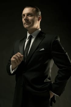 The attractive mature man in black suit on dark studio background