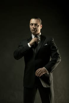The attractive mature man in black suit on dark studio background
