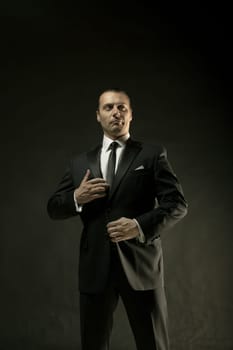 The attractive mature man in black suit on dark studio background