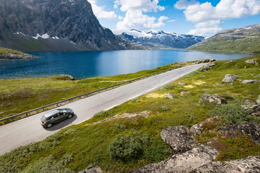 Car in mountains of Norway, Europe. Auto travel through scandinavia. Blue cloudy sky and lake in background.