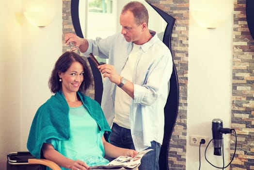 hairdresser cutting hair of woman in his shop