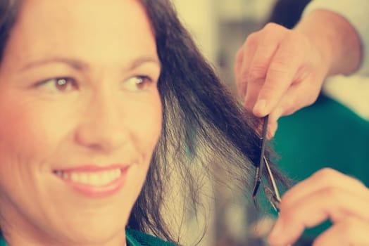 hairdresser cutting hair of woman in his shop