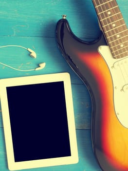 Music concept image, vintage guitar with earphones on a rustic wooden background, Jazz, rock or blues music concept