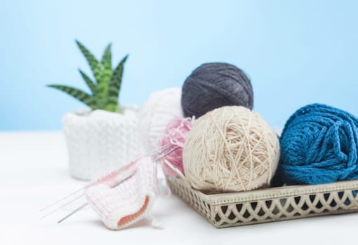 The balls of wool and needles on blue studio background
