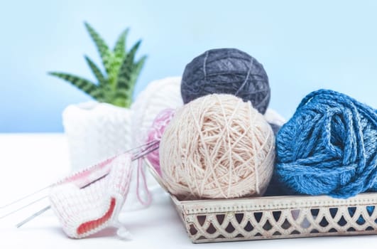 The balls of wool and needles on blue studio background