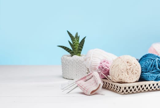 The balls of wool and needles on blue studio background