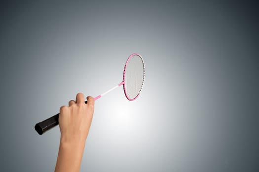 Color photo of one racket for badminton and female hand isolated on gray