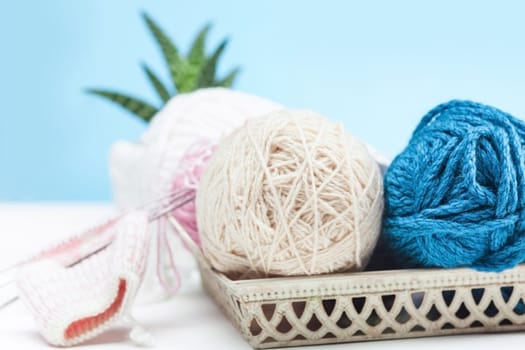 The balls of wool and needles on blue studio background