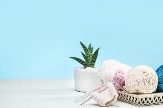 The balls of wool and needles on blue studio background