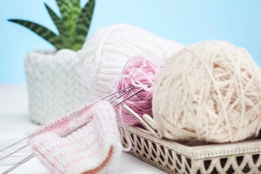 The balls of wool and needles on blue studio background