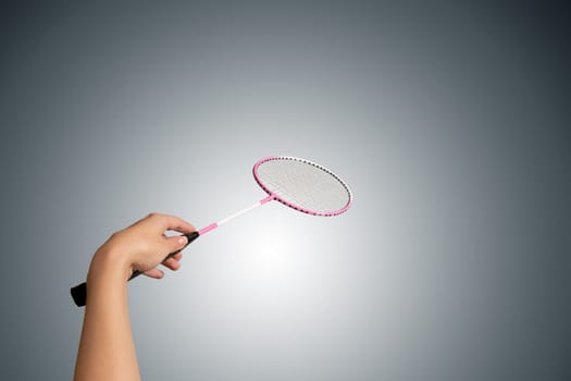 Color photo of one racket for badminton and female hand isolated on gray