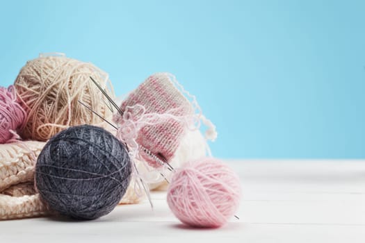 The balls of wool and needles on blue studio background