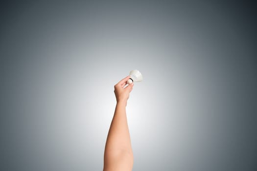 The badminton shuttlecock and female hand isolated with gray background